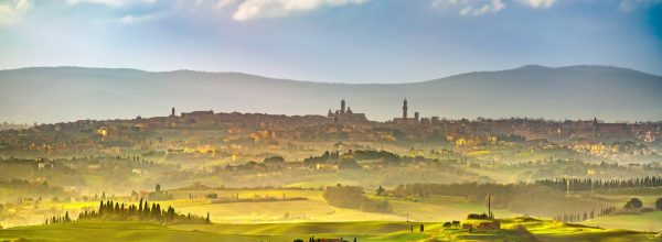 Siena city panoramic skyline, countryside and rolling hills in a misty day. Tuscany, Italy, Europe.